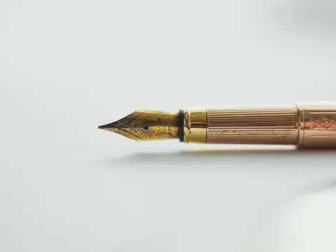 A gold fountain pen resting on a white surface