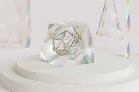 A clear glass geometric object on a white pedestal