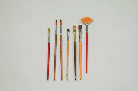 A row of paintbrushes laid out on a pale grey surface