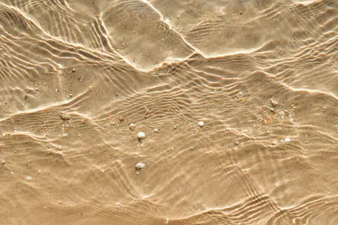 Clear shallow water rippling over golden sand