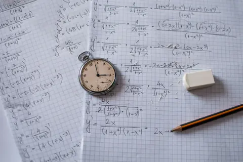 Pocket watch, pencil and eraser on handwritten equations on graph paper