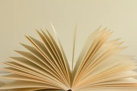 An open book with its pages fanned against a cream background