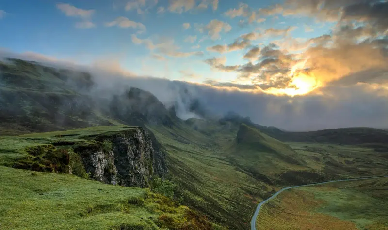 Soft fog drifting across a densely forested green hillside