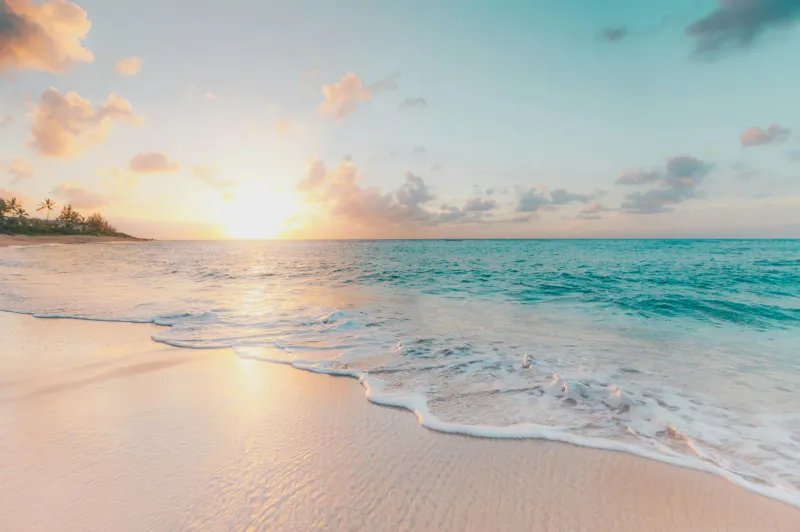 Empty sandy beach curving toward a calm blue sea