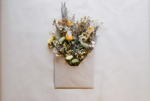A small bouquet of dried flowers tucked into a paper envelope