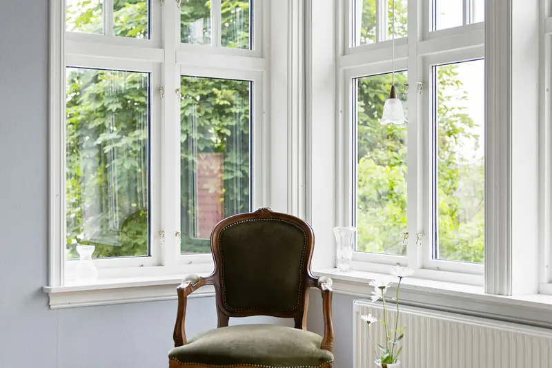 An empty chair beside tall windows