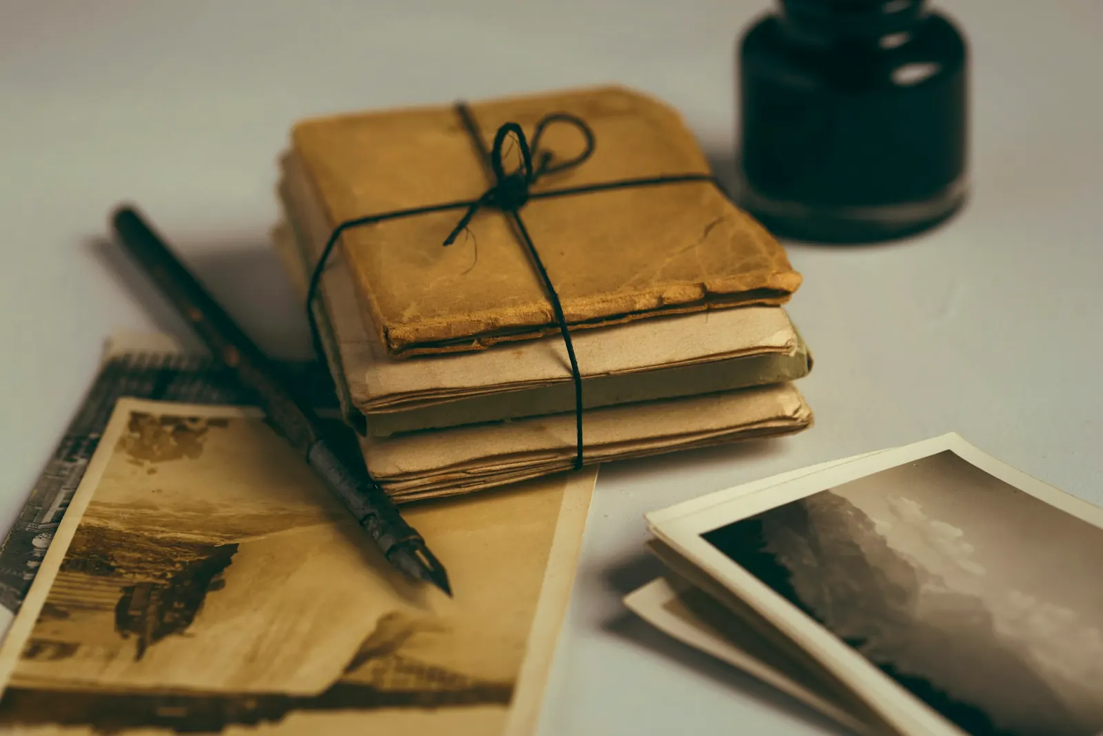 A bundle of old letters tied with string, beside a pen and an ink bottle