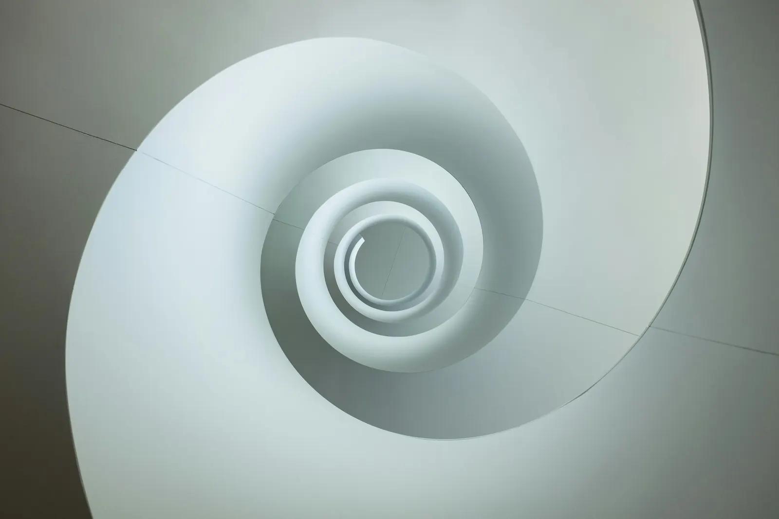 A white spiral staircase seen from above, curling inward