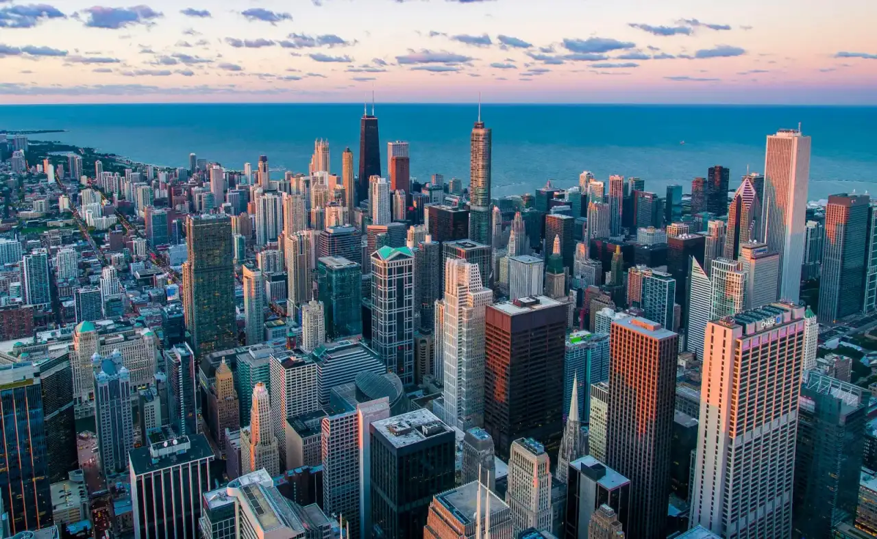 Dense city skyline with lit windows under a dusk sky